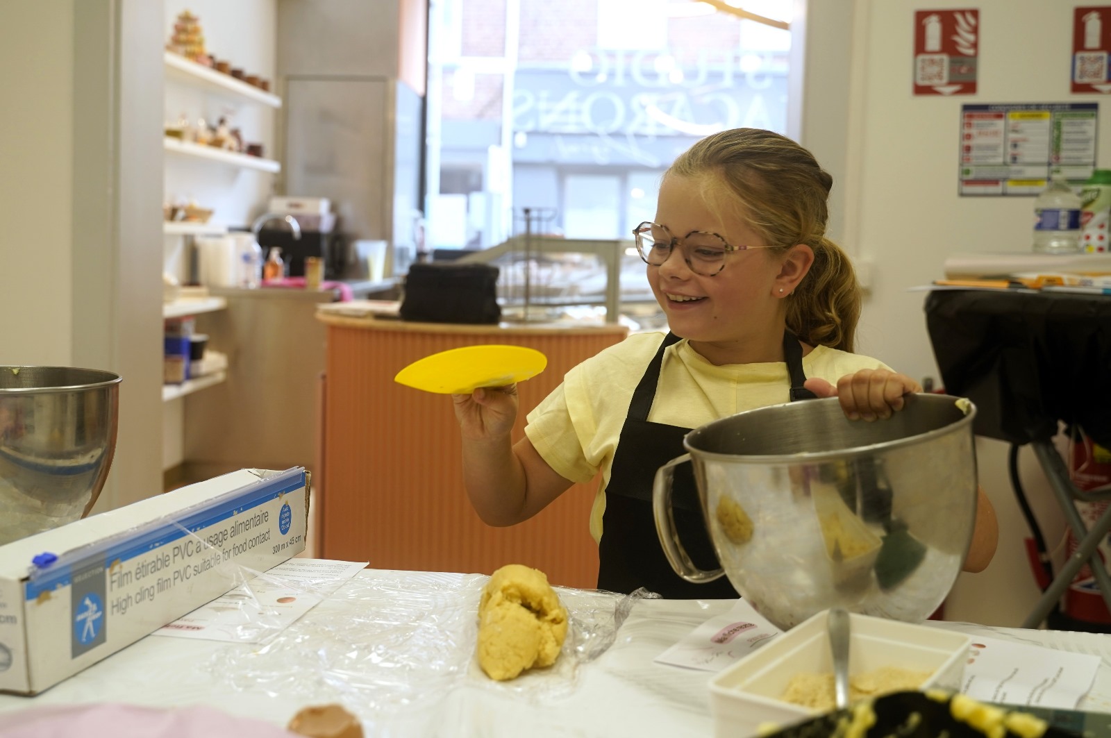 Image site petite fille Une petite fille sourit alors qu'elle sort la pâte à sablés qu'elle vient de malaxer de son pot.